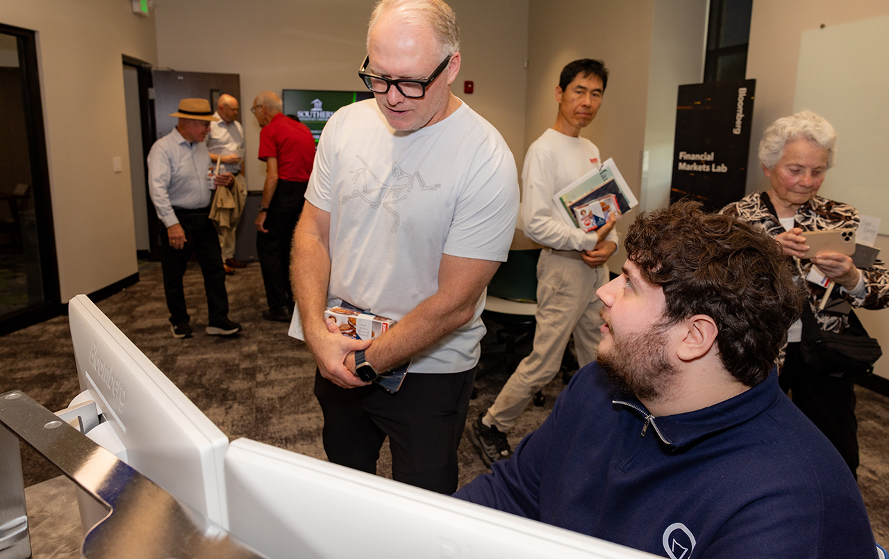 Students demonstrate the financial lab for guests at the Ruth McKee School of Business grand opening.