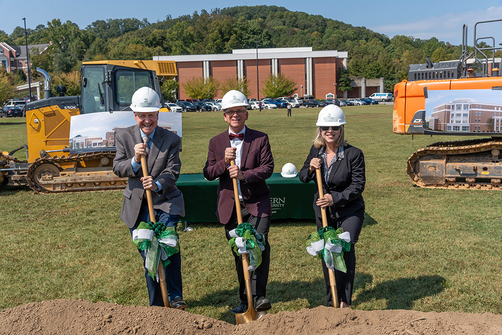 Three people posing with shovels