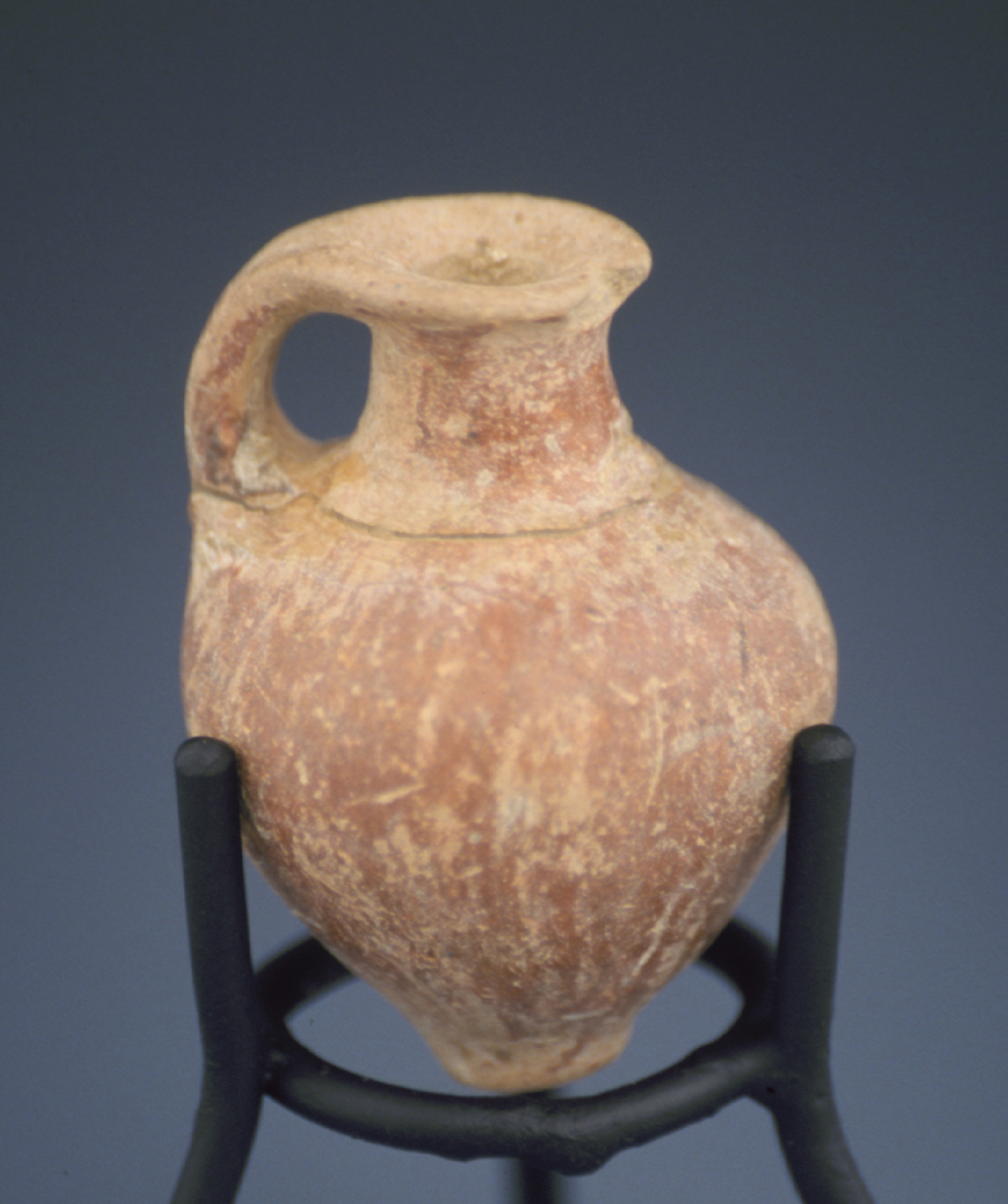 a reddish brown juglet supported by a stand