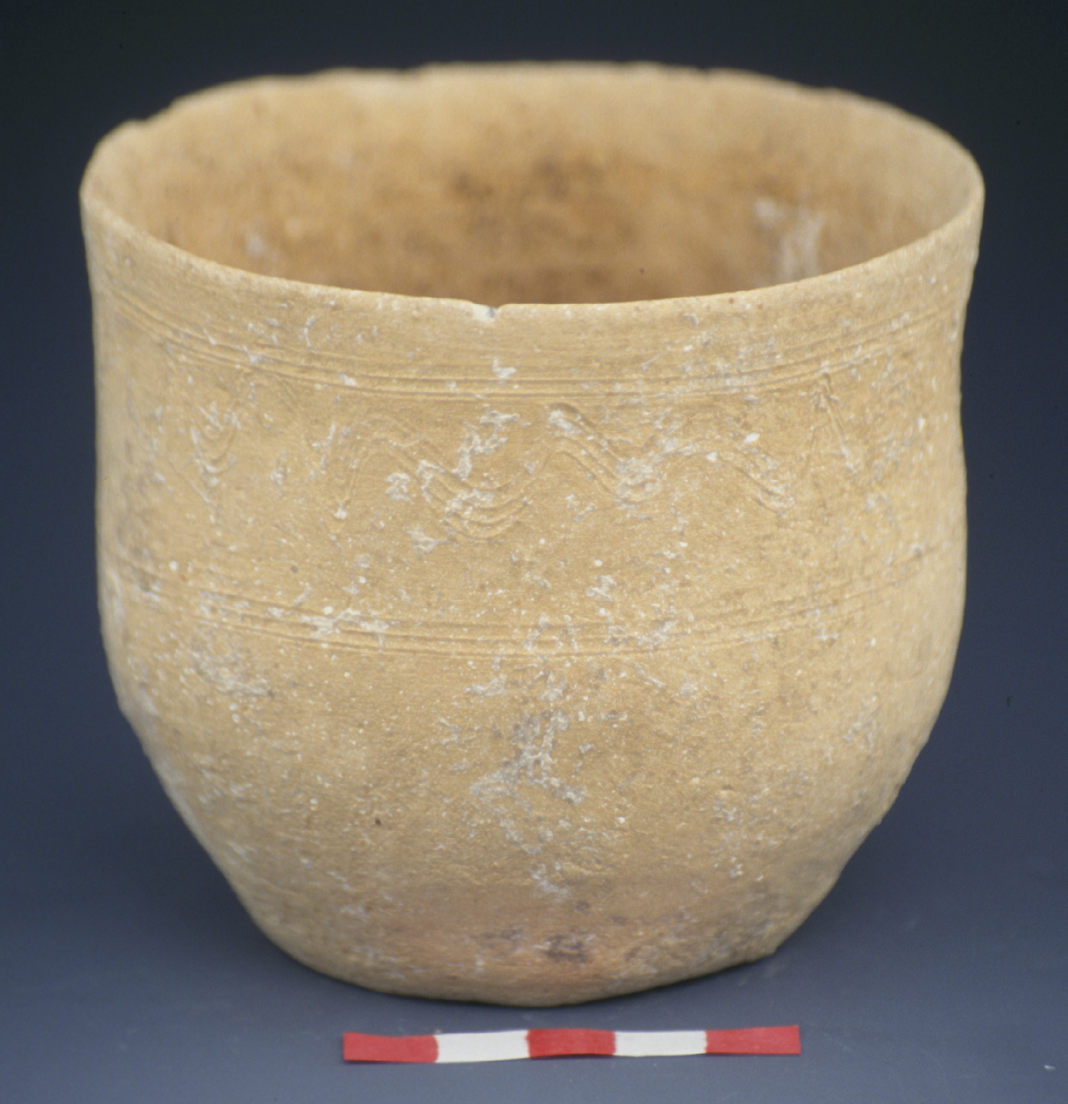 a tan cup with small lines incised at the rim and at the center