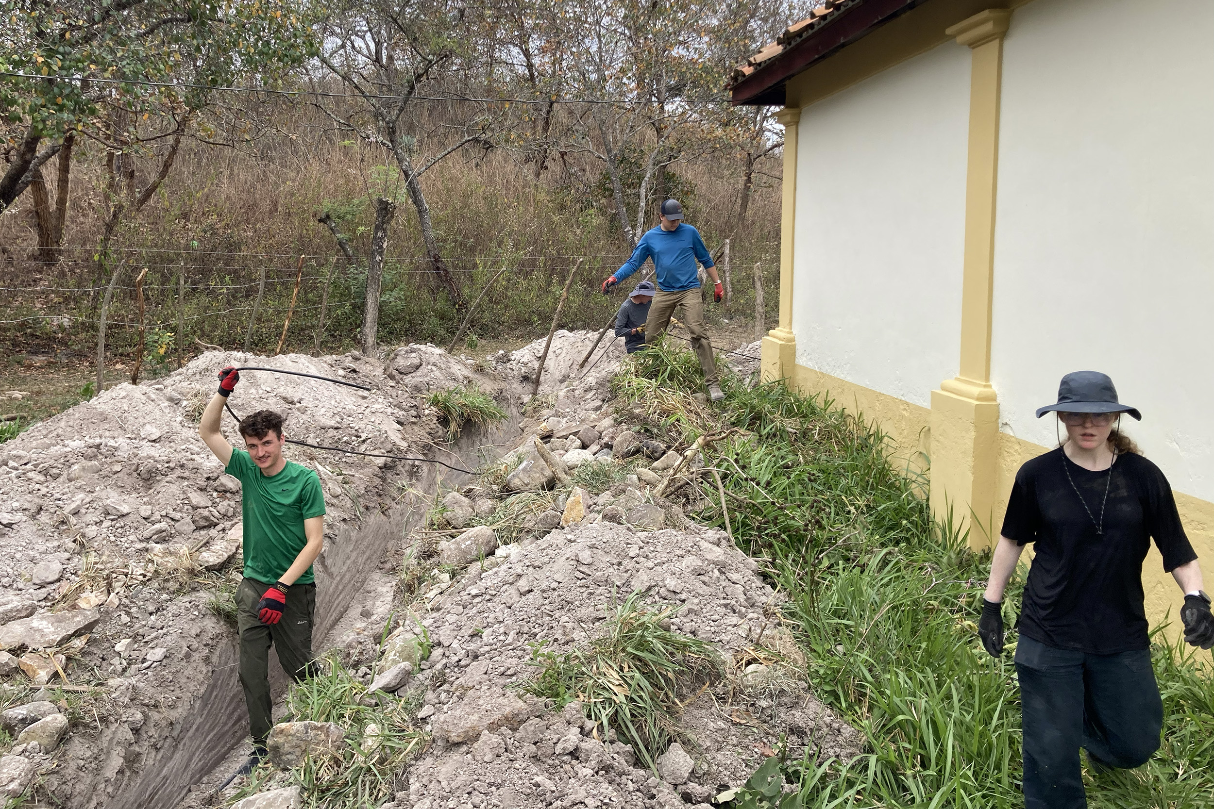 Southern Adventist University students on the engineering mission trip work in a ditch beside a building