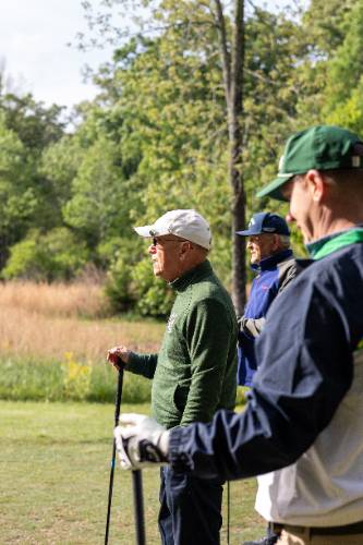 Three golfers watching someone else 