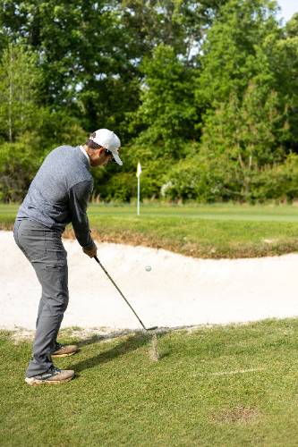 Golfer hitting over a sandtrap 