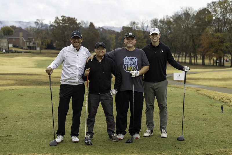 four people posing with golf clubs