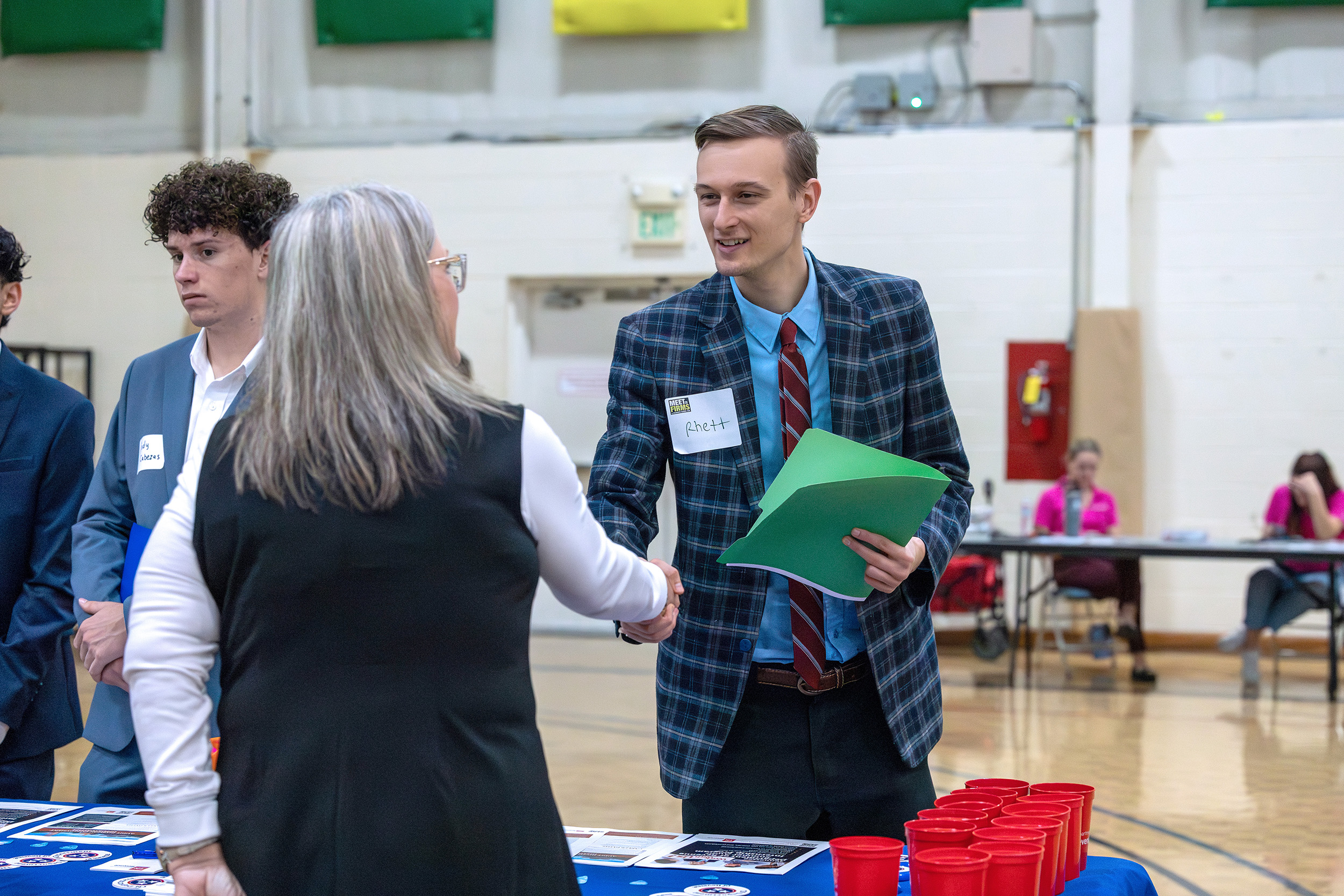 a student shakes hands with a local professional at Meet the Firms