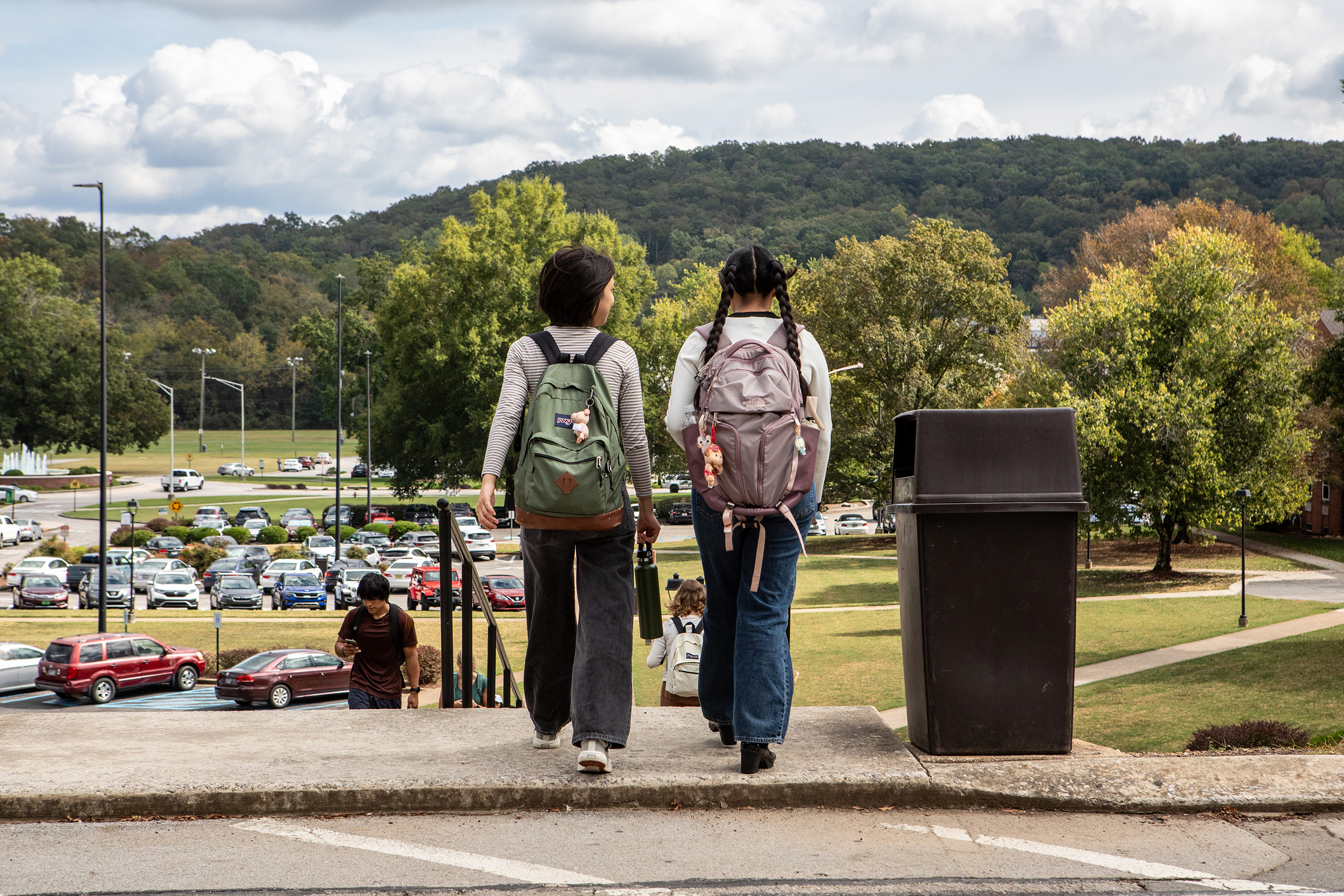two students walk on campus with rolling hills in the background