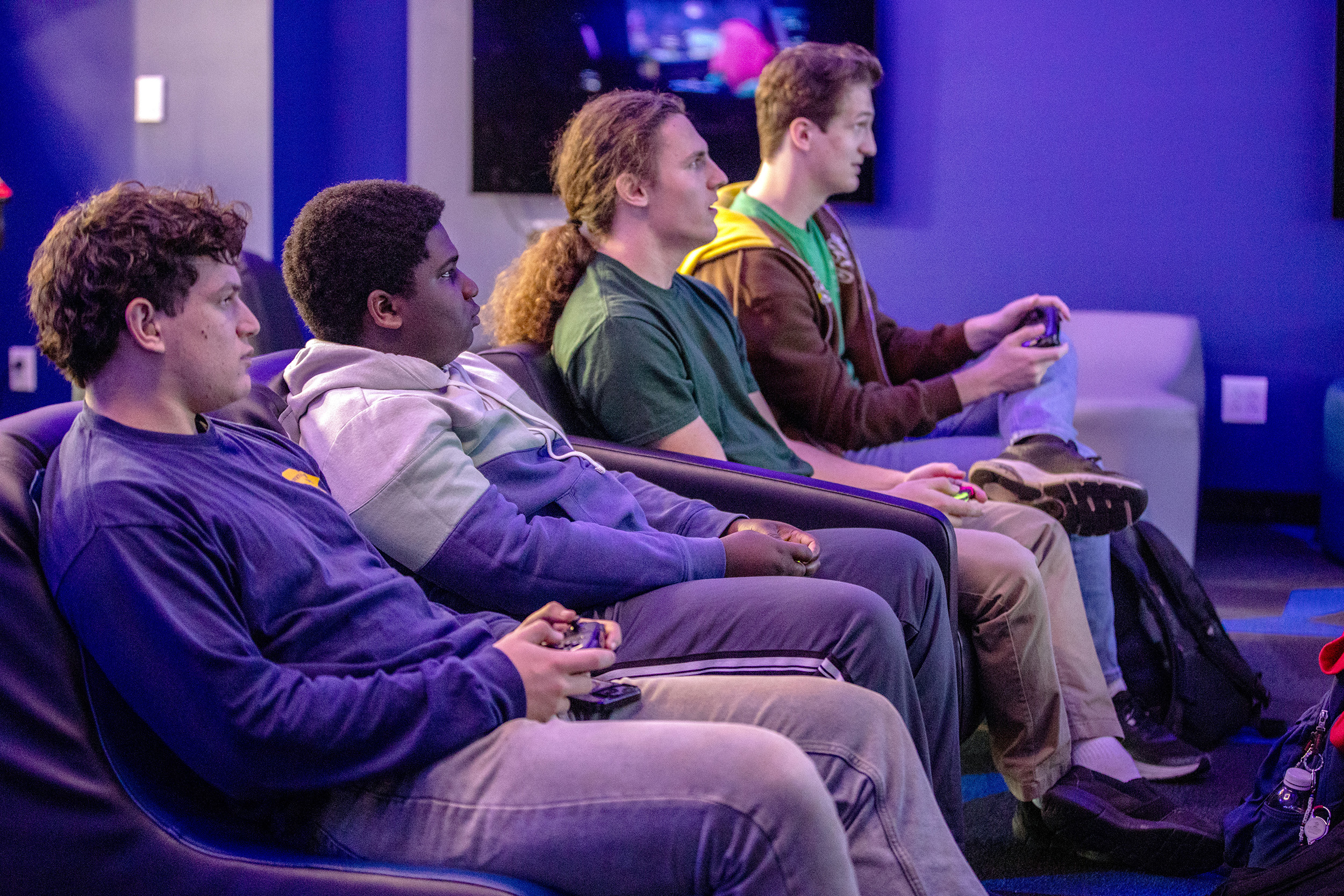 a row of students on a couch play a video game