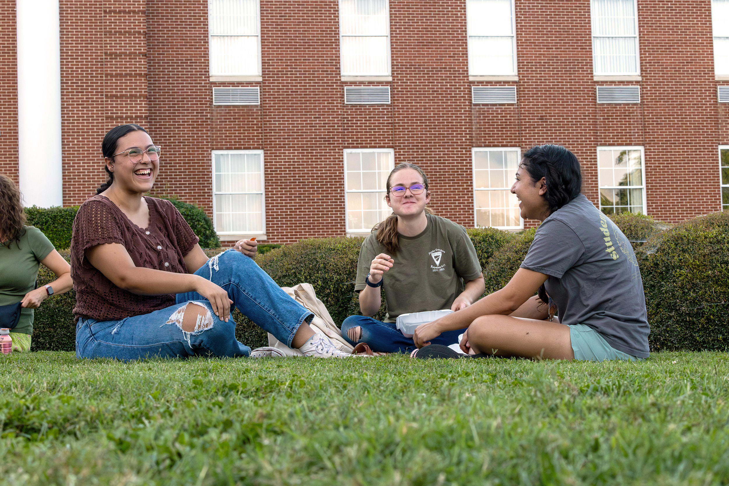 students sitting on the lawn smiling and laughing