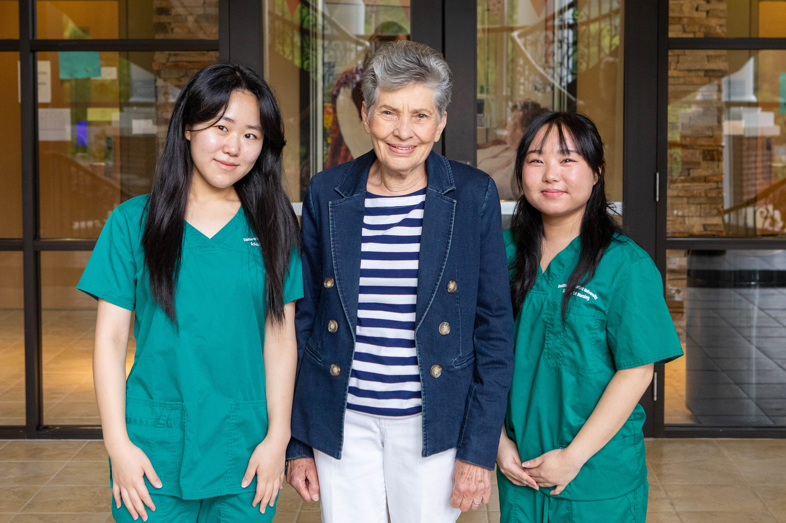 Barbara Smith stands with nursing students on each side of her.