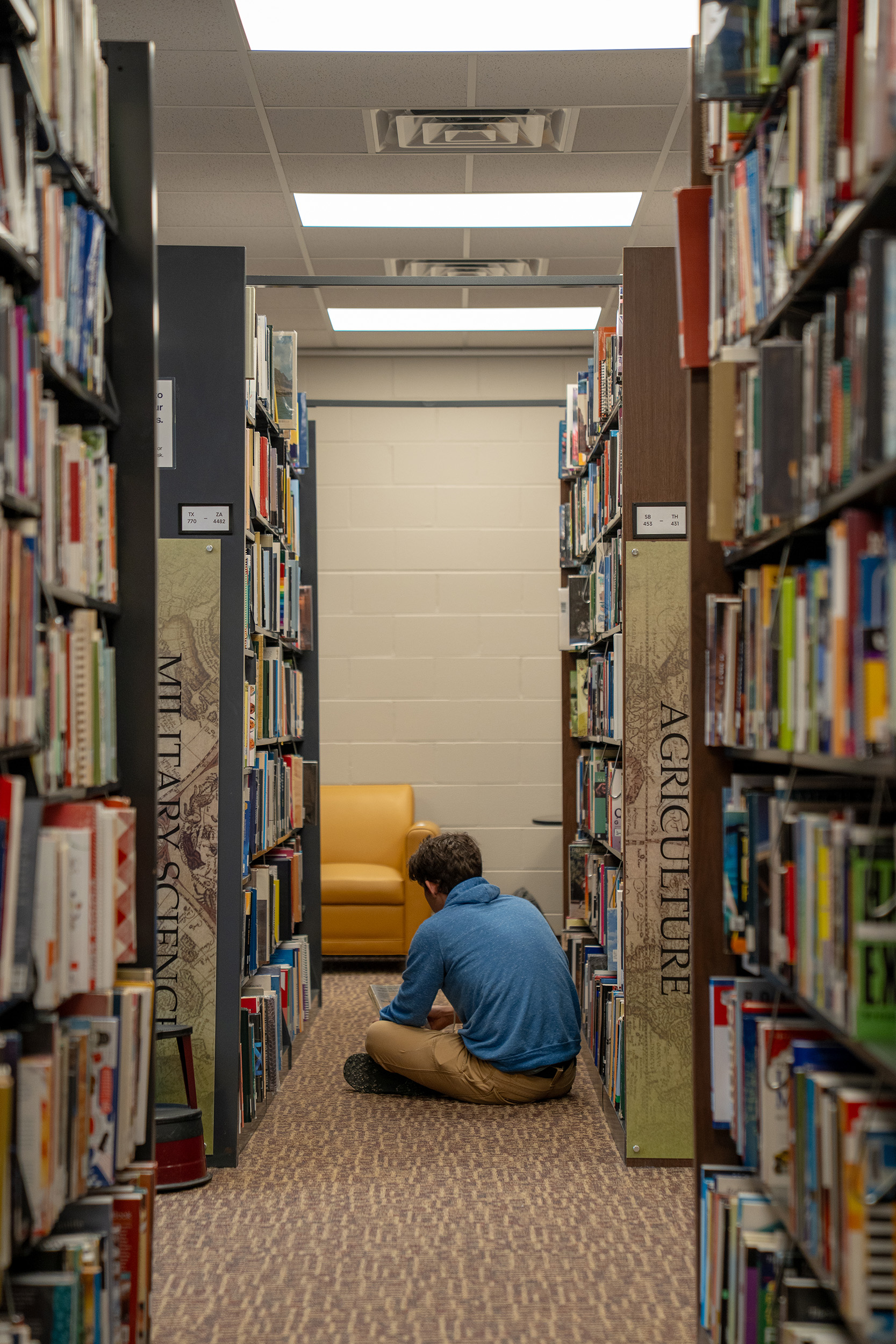student sitting in the library stacks