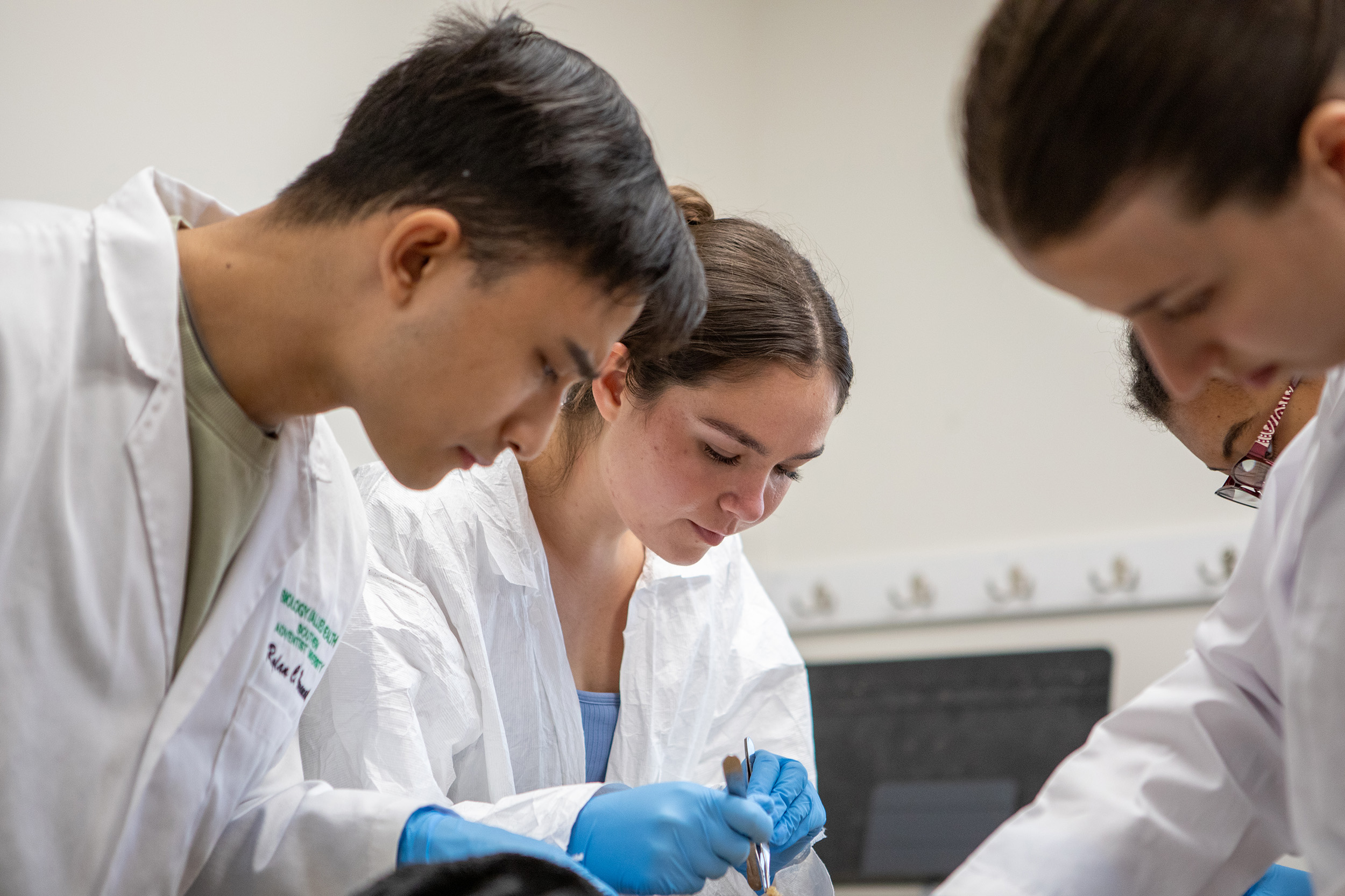 a group of students wearing white coats in a lab