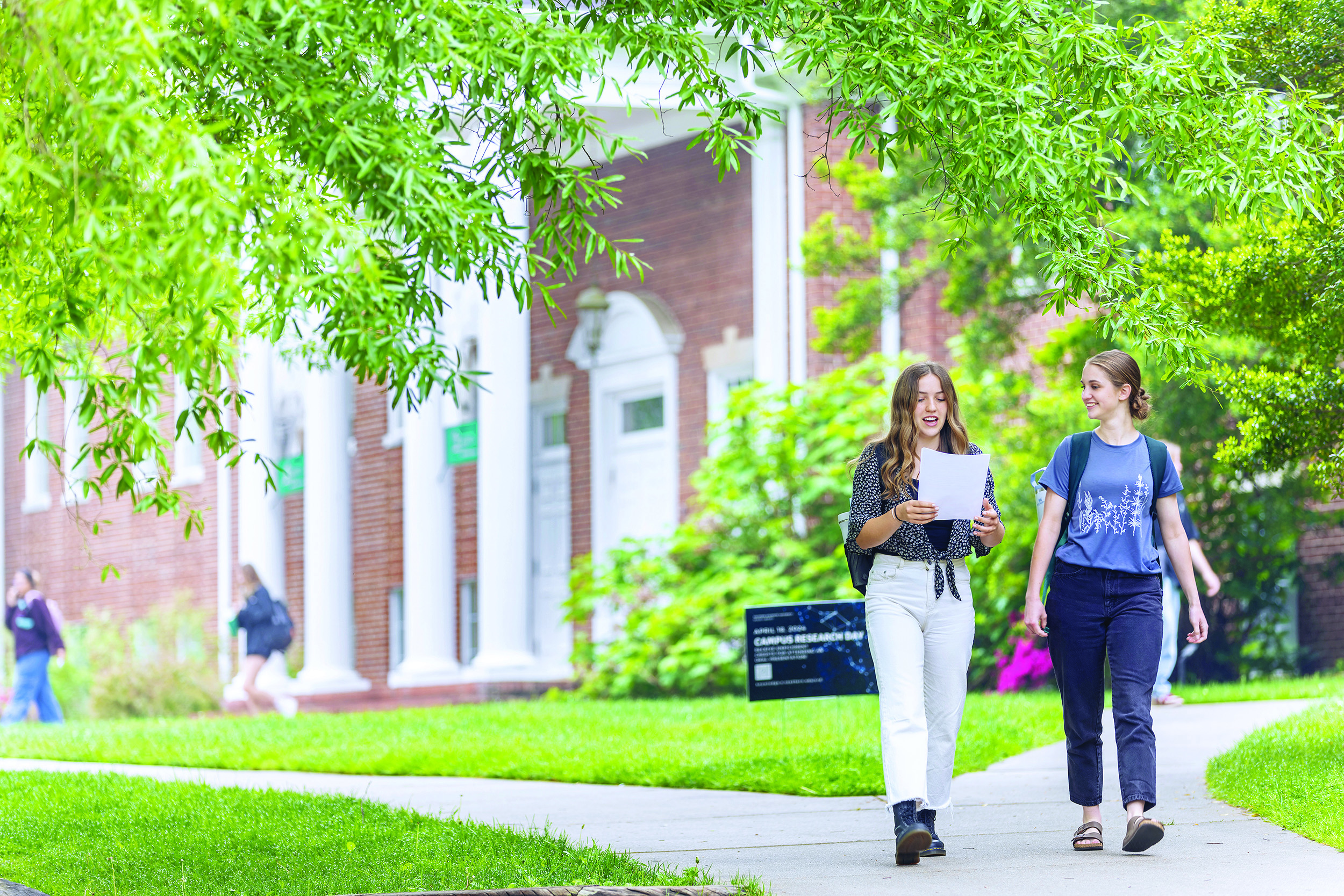 two girls walk together on the sidewalk