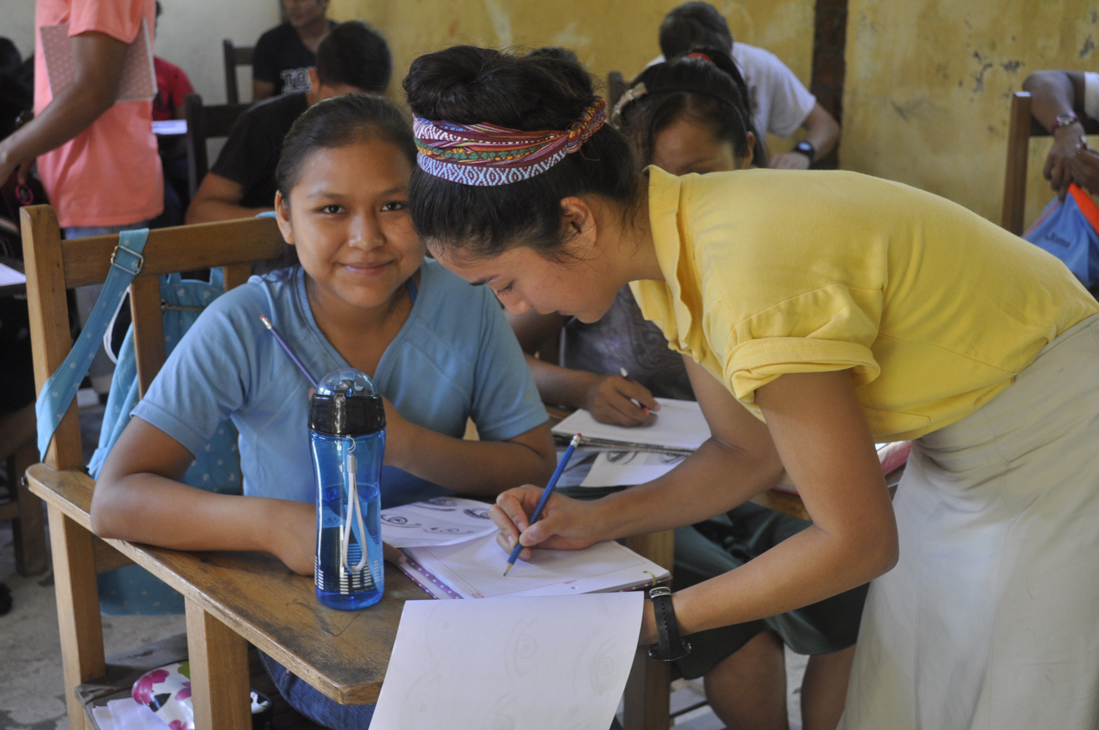 A Southern volunteer helps a Bolivian student at her desk