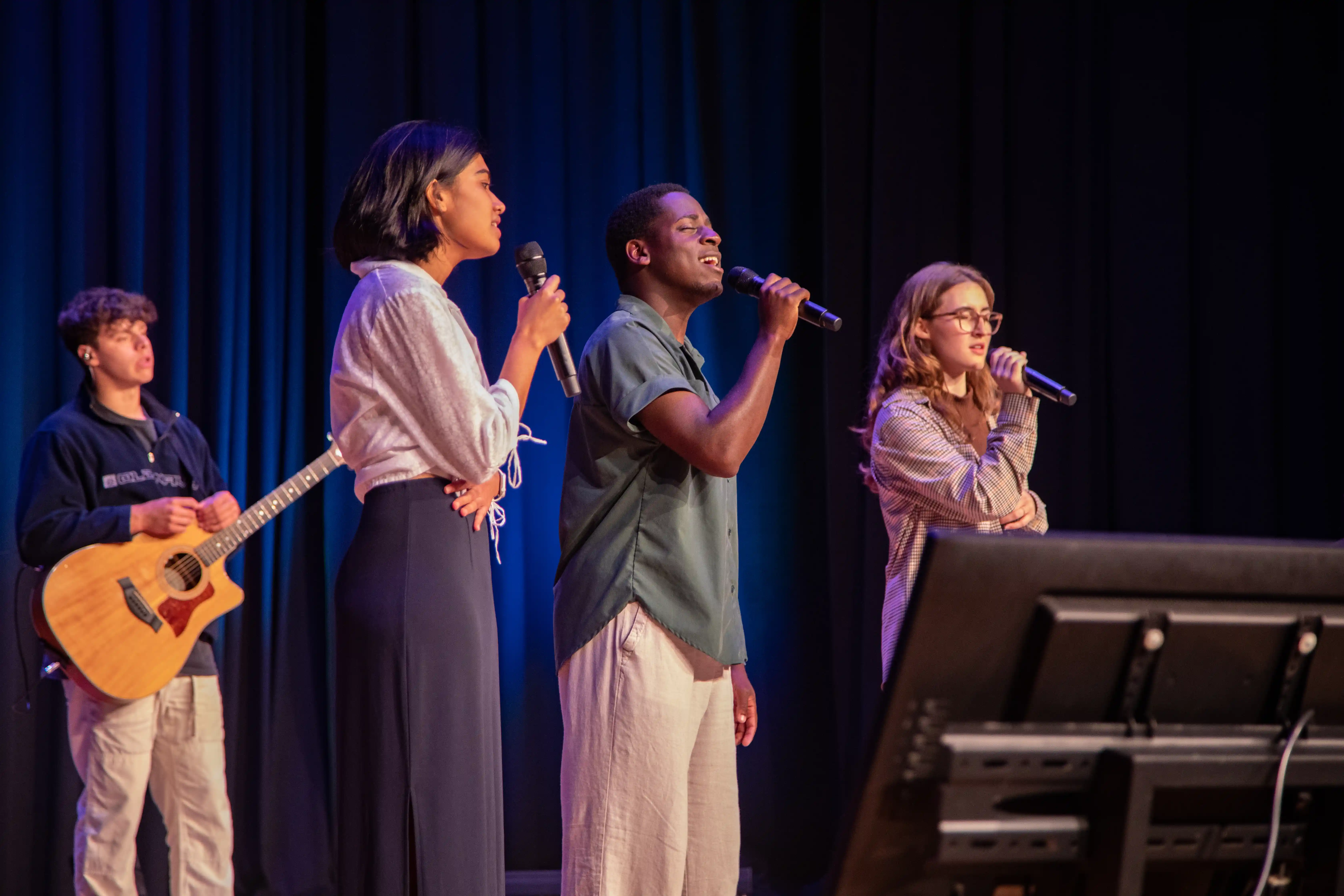 Four students singing Christan music on a stage