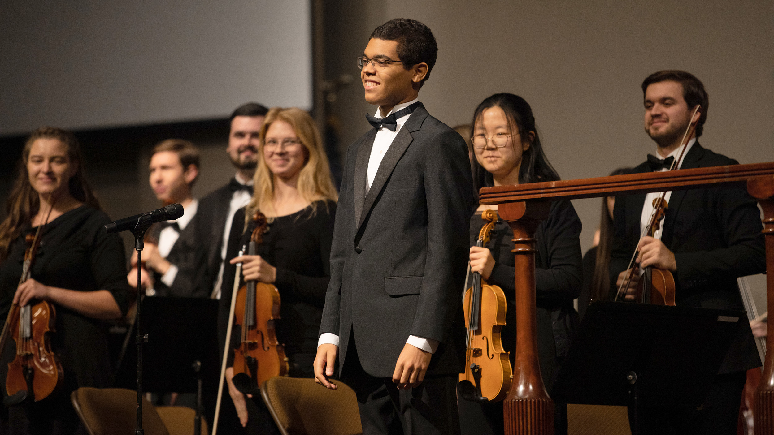 Student Composer Matthew Kimbley smiles on stage after conducting an original composition