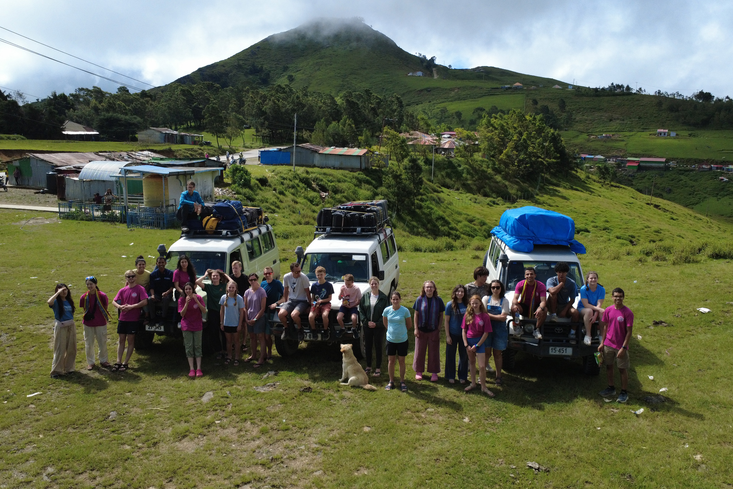 Mission volunteers stand in a field by vans
