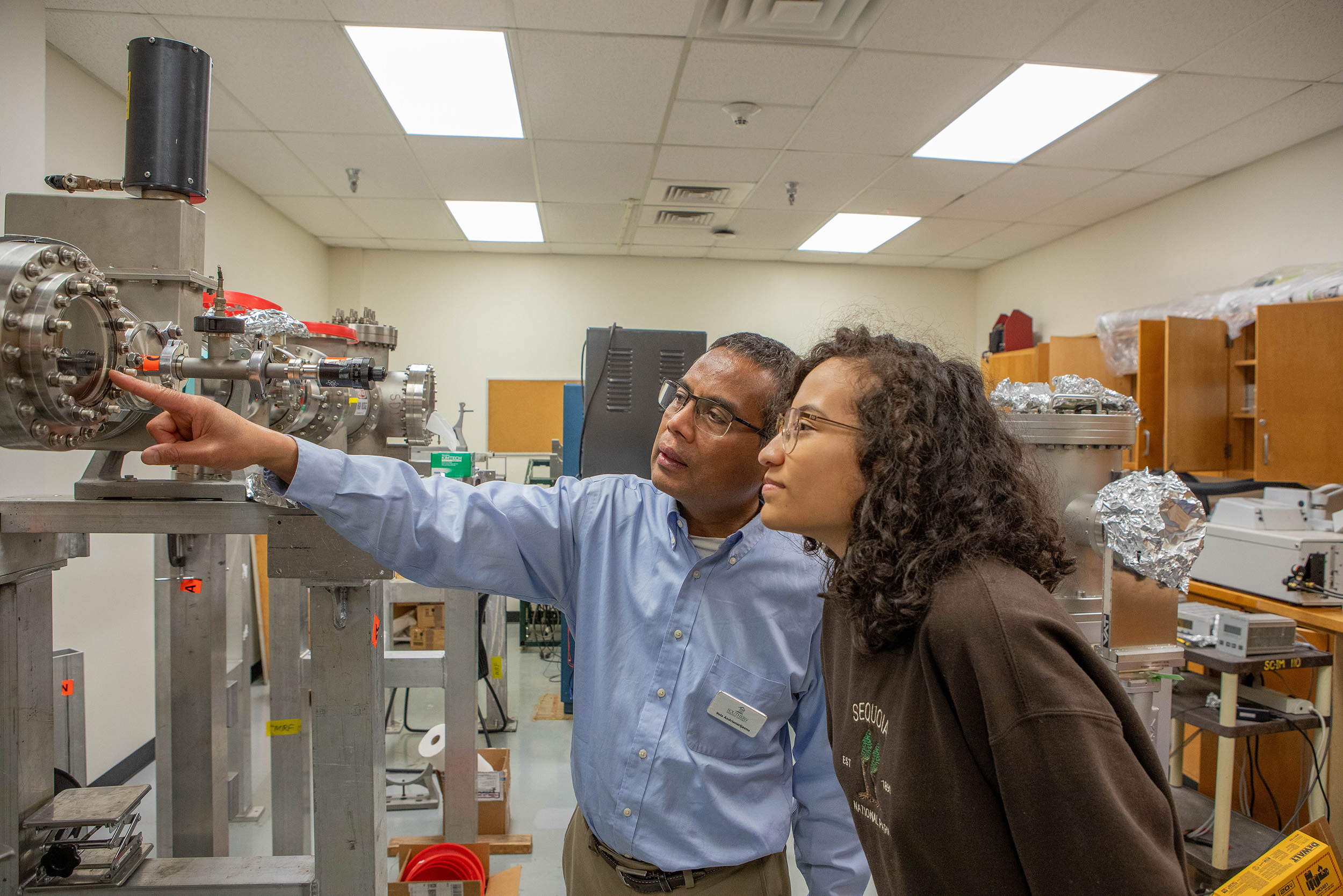 Professor and student work with the beamline for ion-neutral collisions