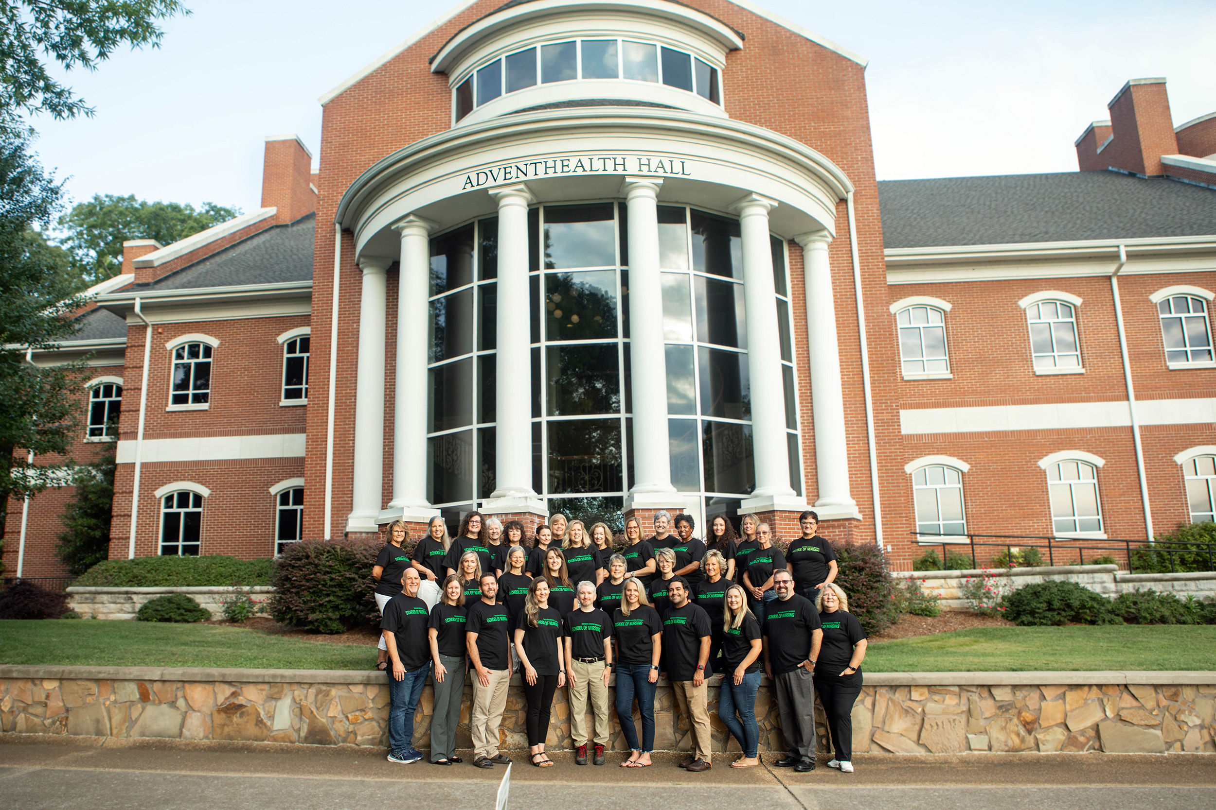 faculty stand in front of Advent Health Hall on campus