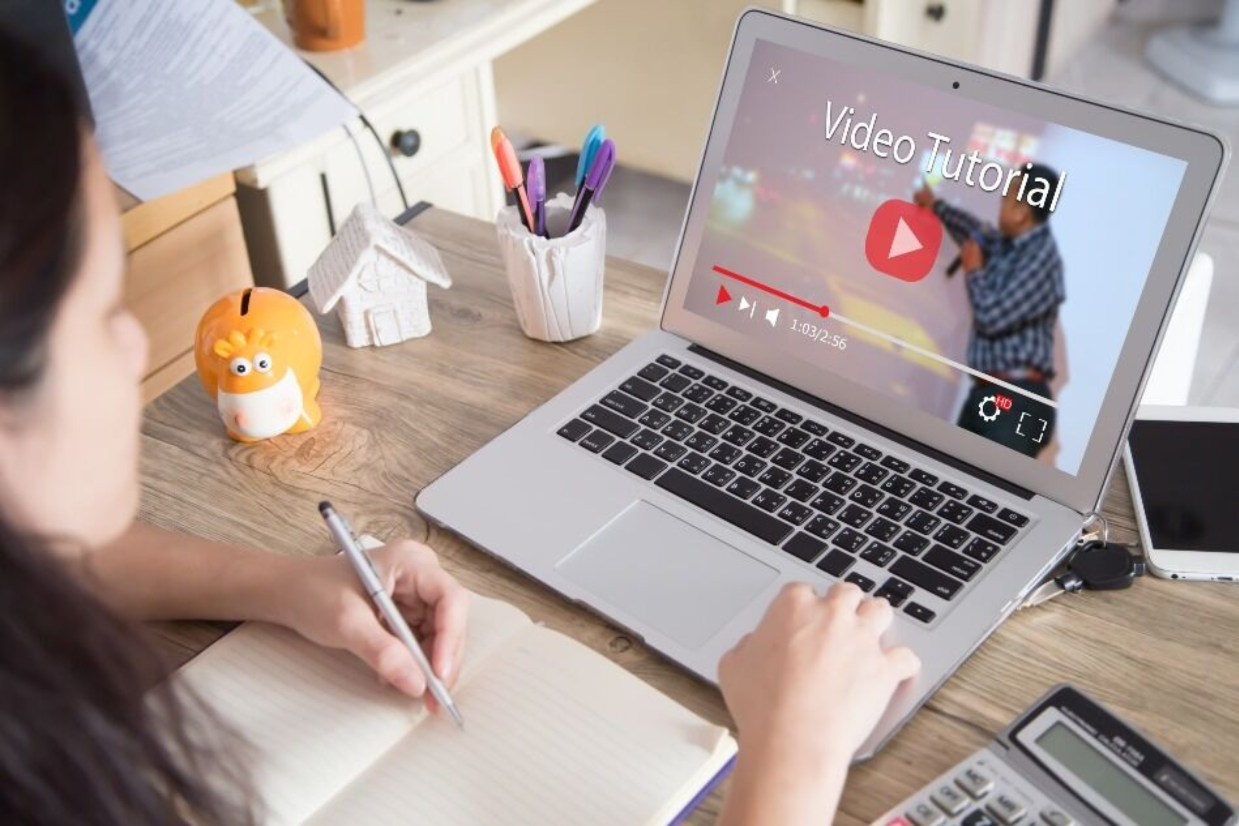 Person watching tutorial on laptop at a desk.