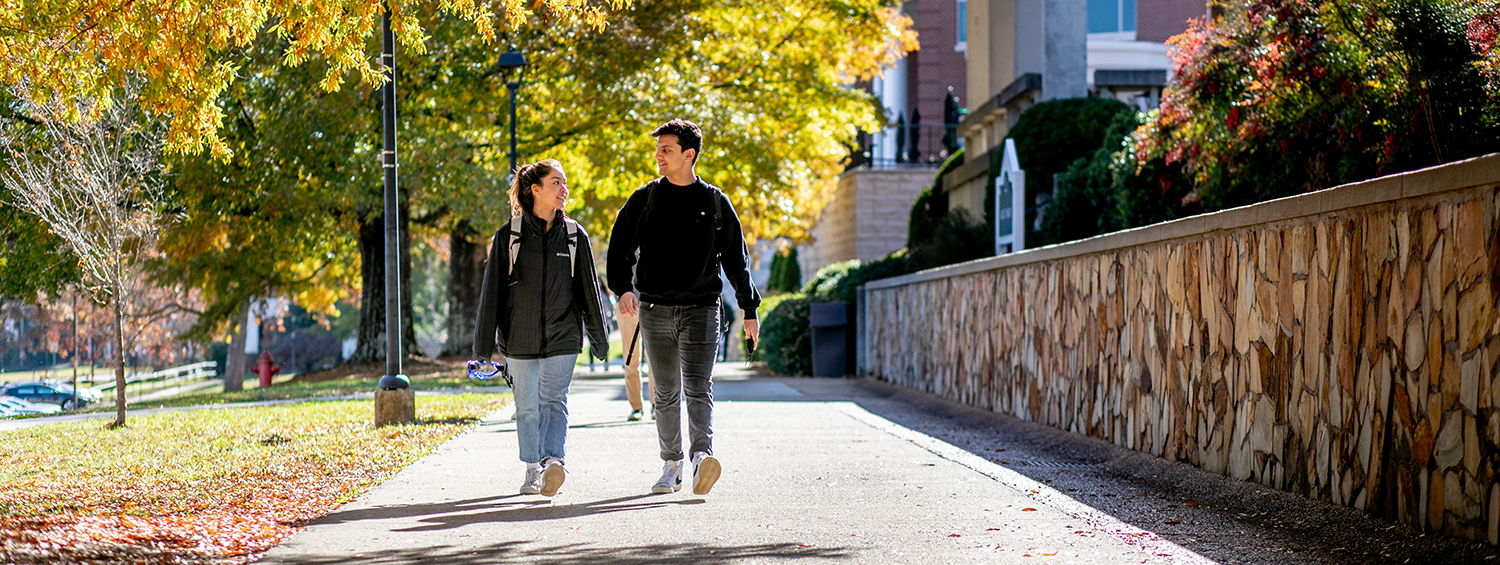 Two students stroll on the promenade together.